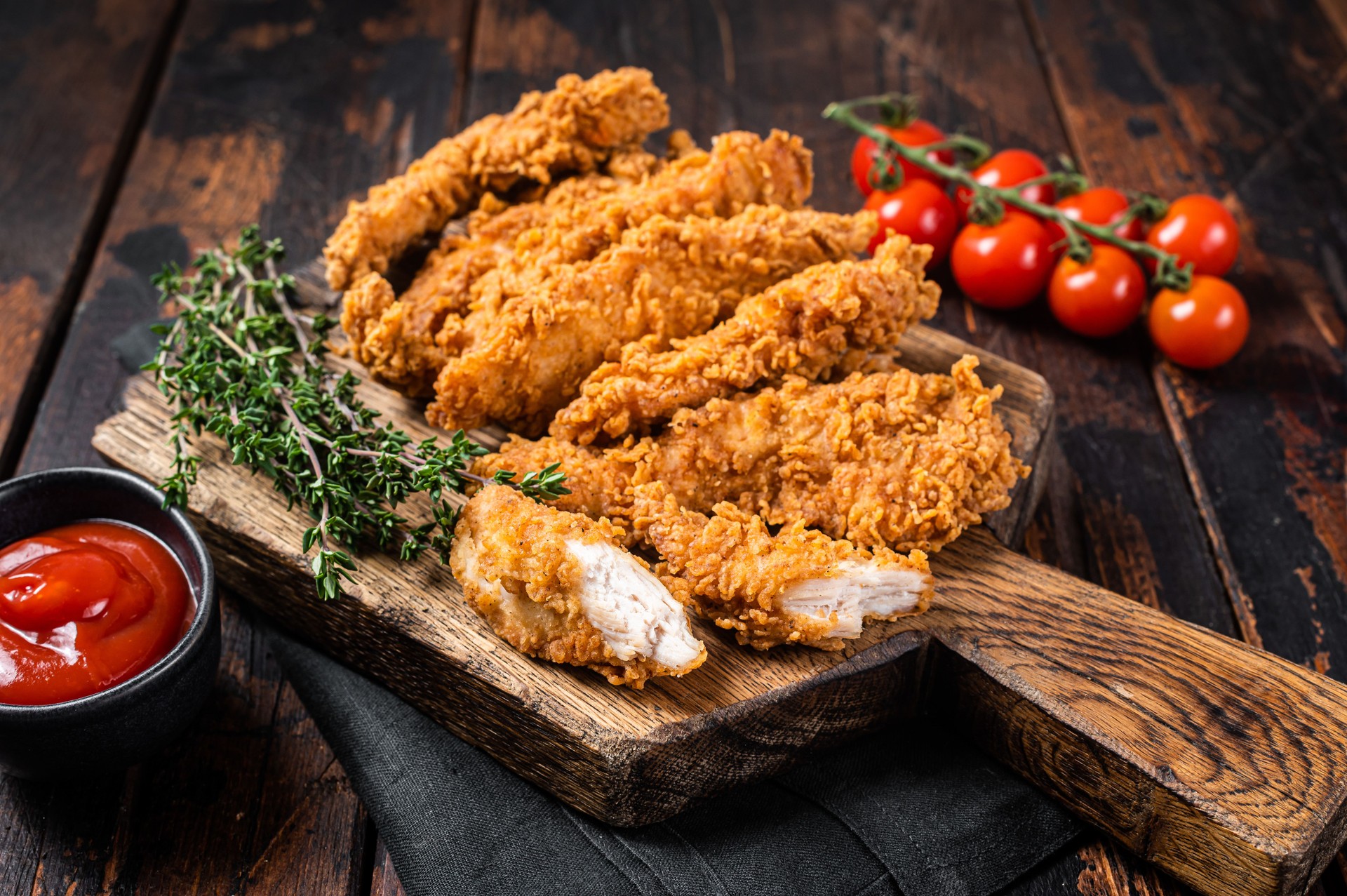 Crispy fried Breaded chicken strips, breast fillet meat with tomato ketchup on a plate. Wooden backgrund. Top view
